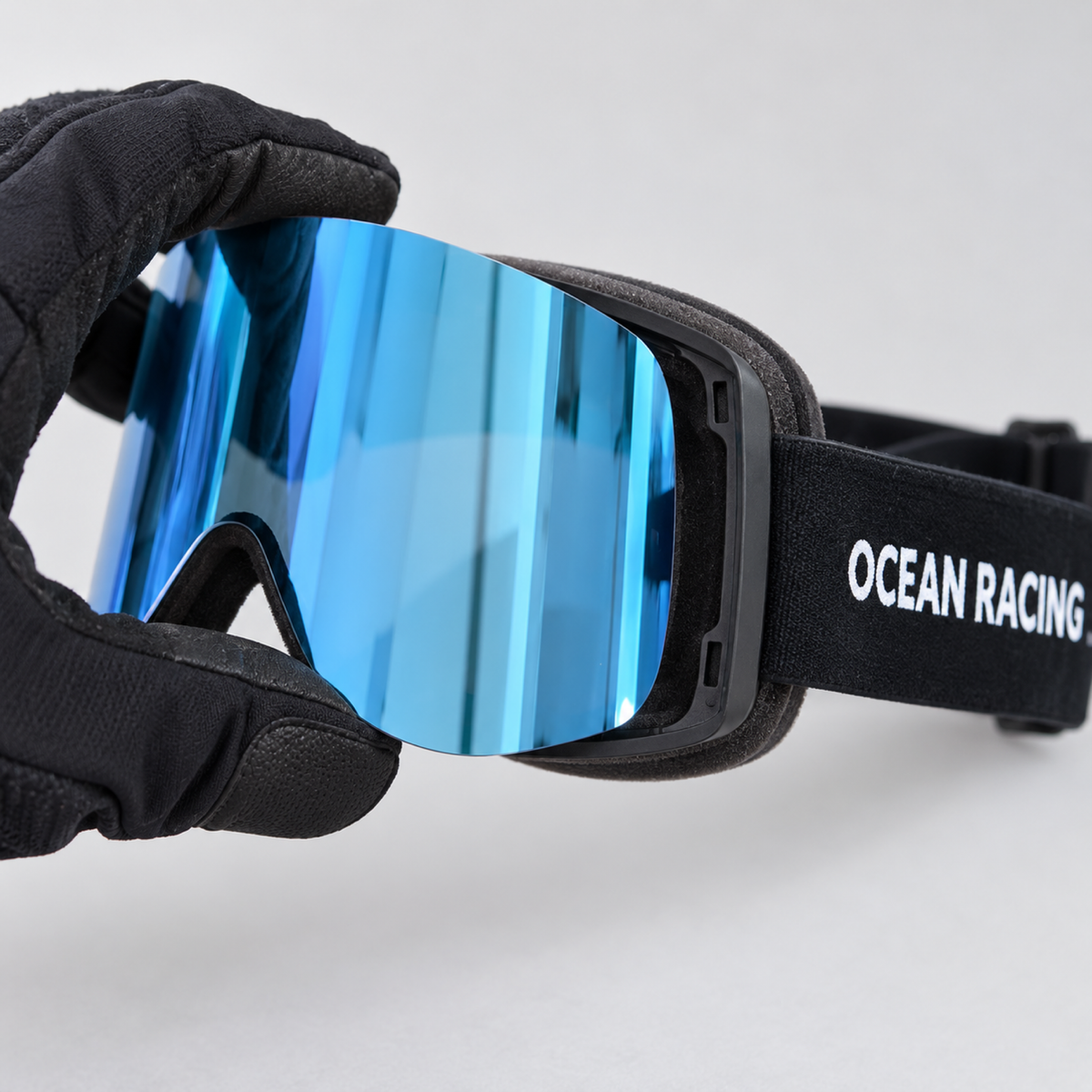 Gloved hands swapping the magnetic lens on the Ocean Racing ORG goggle